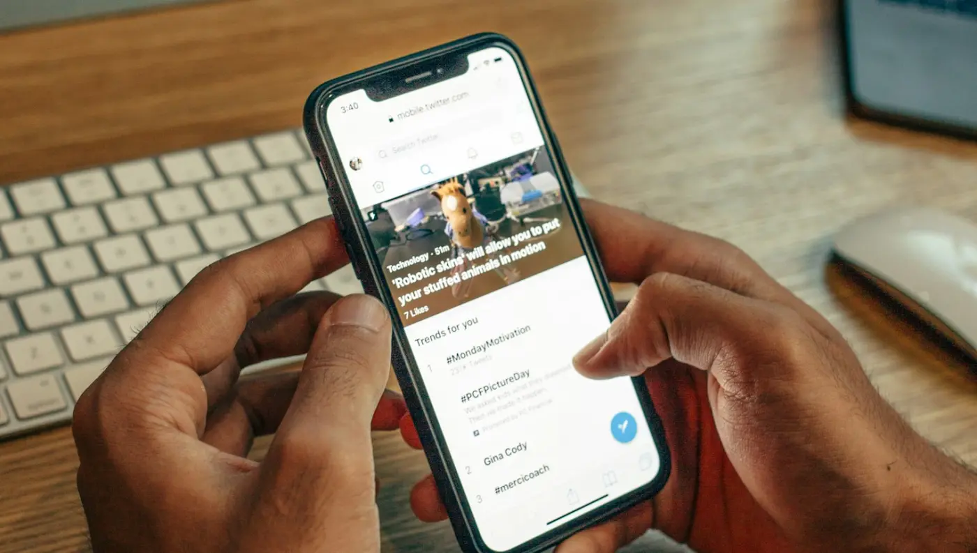 Hands holding an iPhone above a desk